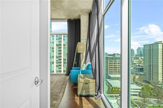 doorway to outside featuring a wall of windows, a view of city, and wood finished floors