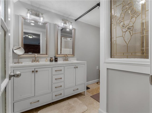 full bathroom with tile patterned flooring, a sink, baseboards, and double vanity