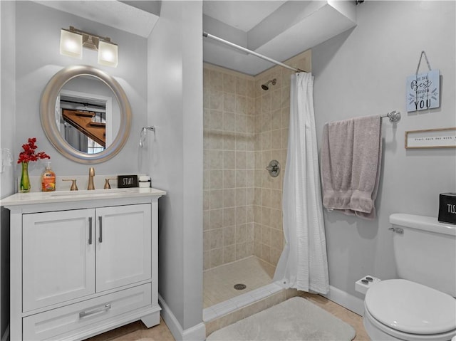 bathroom with vanity, a shower stall, toilet, and baseboards