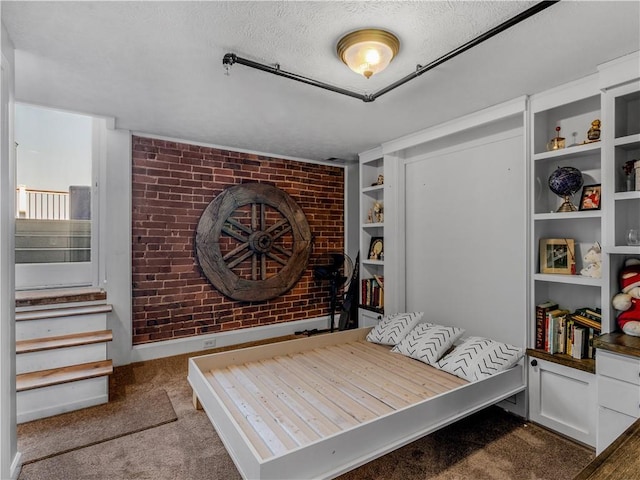 bedroom with brick wall, carpet, and a textured ceiling