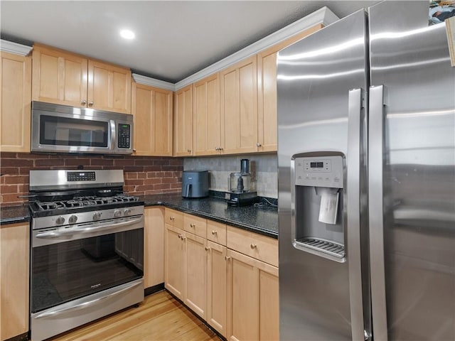 kitchen featuring stainless steel appliances, light brown cabinetry, dark stone countertops, and tasteful backsplash