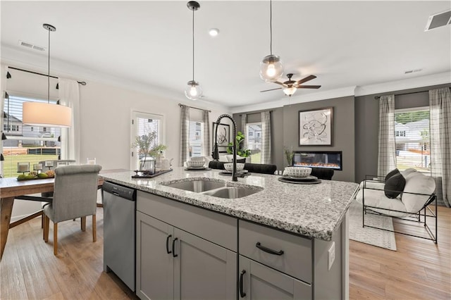 kitchen featuring a wealth of natural light, a center island with sink, decorative light fixtures, and light hardwood / wood-style floors