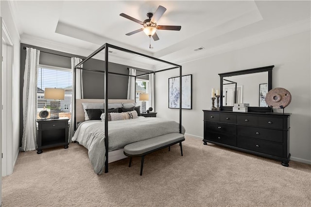 carpeted bedroom with ceiling fan and a raised ceiling