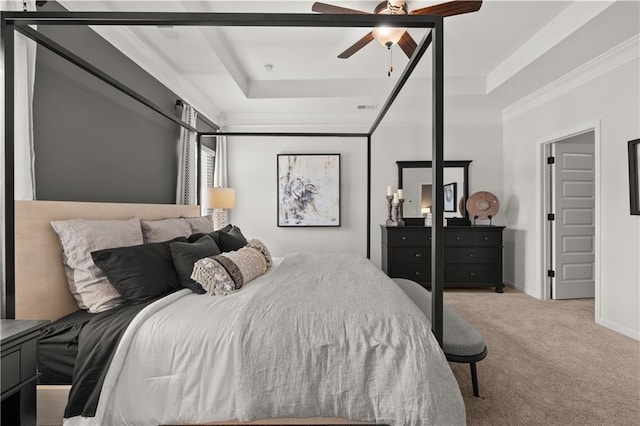 carpeted bedroom with ceiling fan, ornamental molding, and a tray ceiling