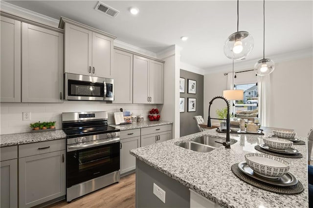 kitchen featuring sink, gray cabinets, crown molding, appliances with stainless steel finishes, and decorative light fixtures