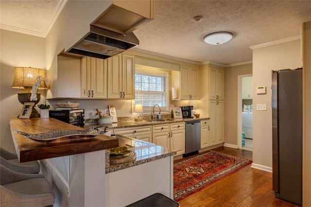 kitchen featuring a textured ceiling, stainless steel appliances, sink, stone countertops, and range hood