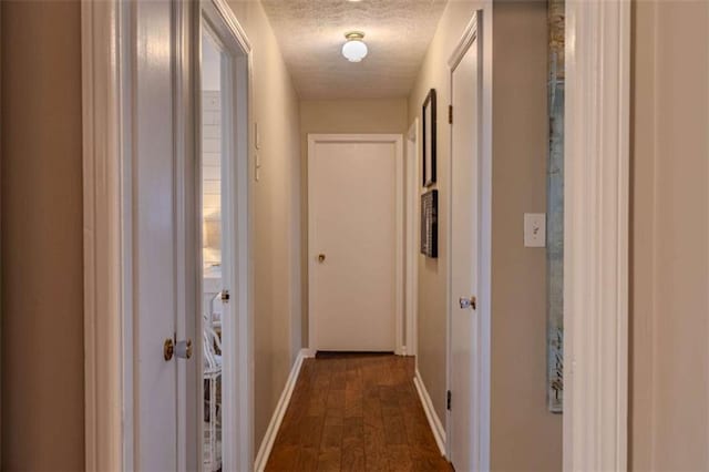 corridor featuring dark wood-type flooring and a textured ceiling