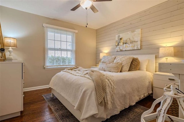 bedroom featuring ceiling fan, dark hardwood / wood-style flooring, and wood walls