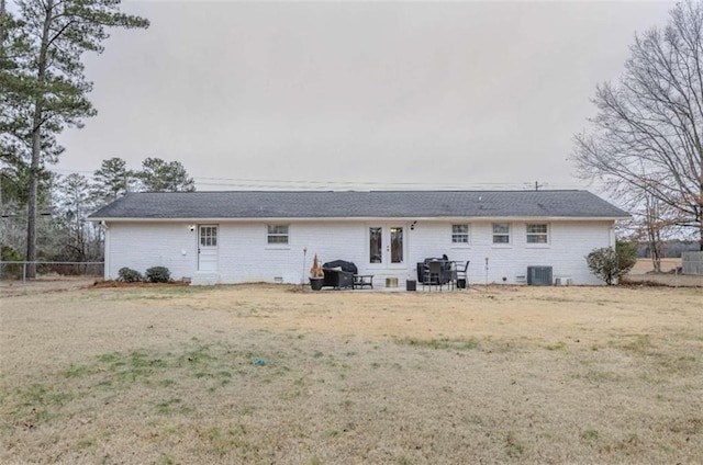 back of house with central AC unit and a lawn