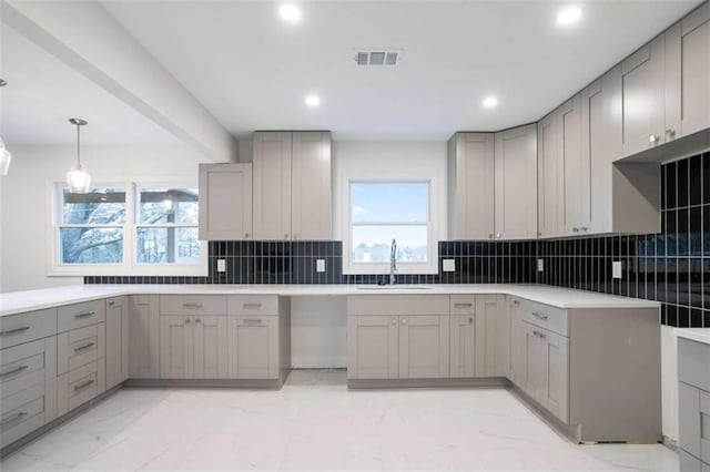 kitchen featuring sink, decorative light fixtures, tasteful backsplash, and gray cabinetry