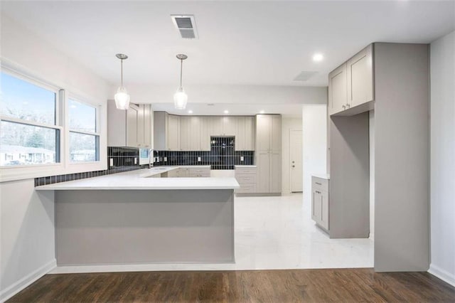 kitchen with pendant lighting, backsplash, gray cabinets, and kitchen peninsula