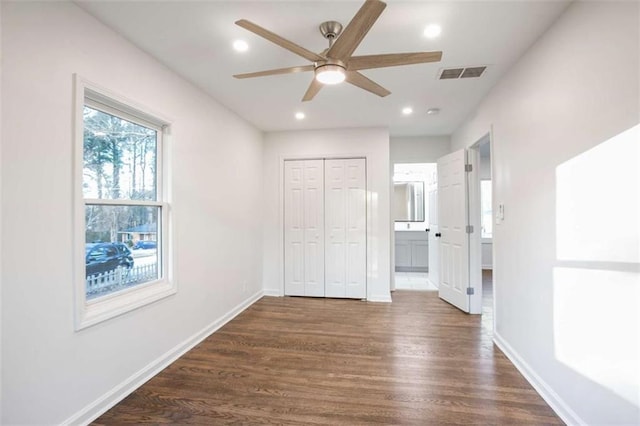 unfurnished bedroom with dark wood-type flooring, ceiling fan, a closet, and connected bathroom