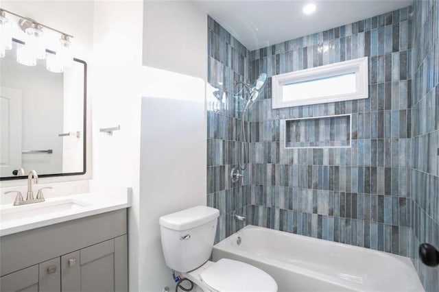 full bathroom featuring tiled shower / bath, vanity, and toilet