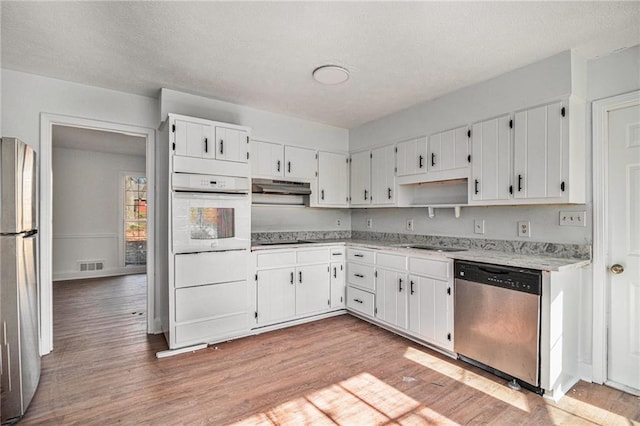 7935 Sweetwater Dr, Douglasville, GA 30135 - kitchen featuring stainless steel appliances, under cabinet range hood, light wood-type flooring, a textured ceiling, and white cabinetry