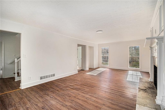 7935 Sweetwater Dr, Douglasville, GA 30135 - unfurnished living room featuring a textured ceiling, wood finished floors, a brick fireplace, stairs, and ornamental molding