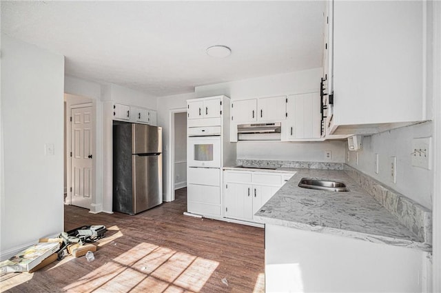 7935 Sweetwater Dr, Douglasville, GA 30135 - kitchen with freestanding refrigerator, white oven, under cabinet range hood, black electric stovetop, and dark wood finished floors