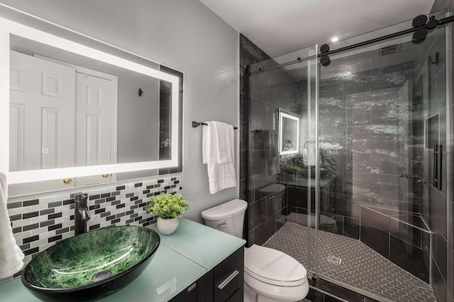 bathroom featuring toilet, backsplash, vanity, and a shower with door