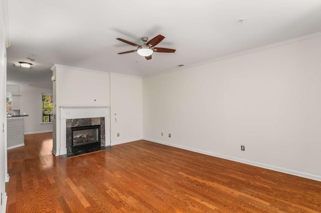 unfurnished living room with a fireplace, ornamental molding, ceiling fan, and wood-type flooring