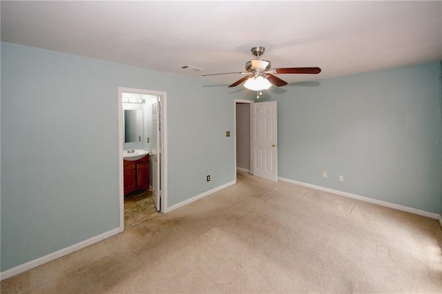 unfurnished bedroom with carpet, baseboards, a sink, connected bathroom, and a ceiling fan