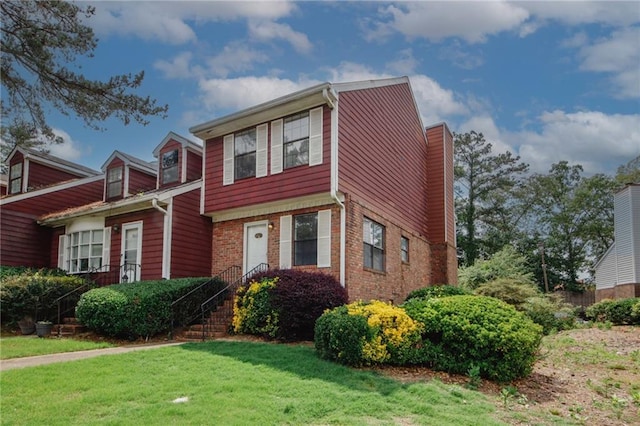 view of front of property featuring a front yard, a chimney, and brick siding