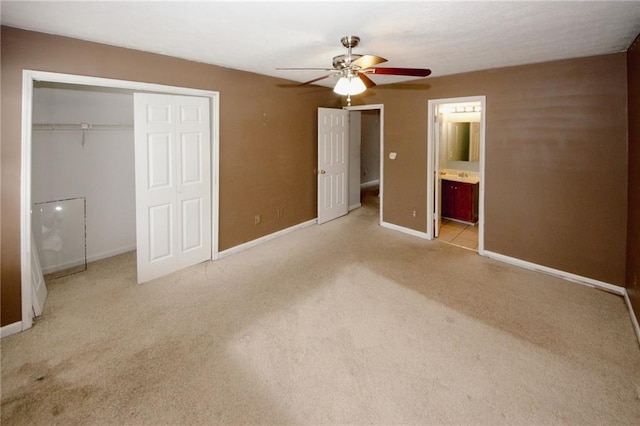 unfurnished bedroom with light carpet, baseboards, a closet, ensuite bathroom, and ceiling fan