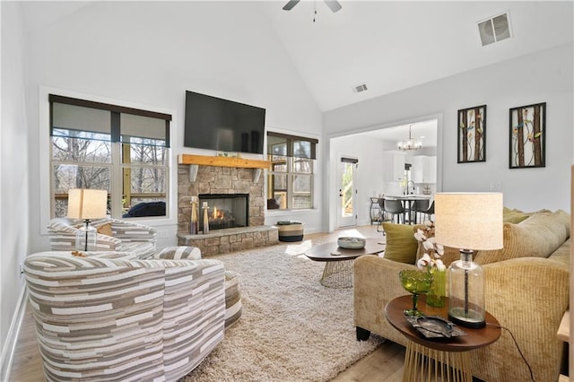 living room featuring ceiling fan with notable chandelier, a fireplace, hardwood / wood-style flooring, and high vaulted ceiling