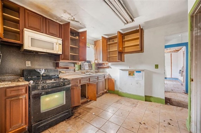 kitchen featuring light tile patterned flooring, sink, gas stove, light stone counters, and backsplash