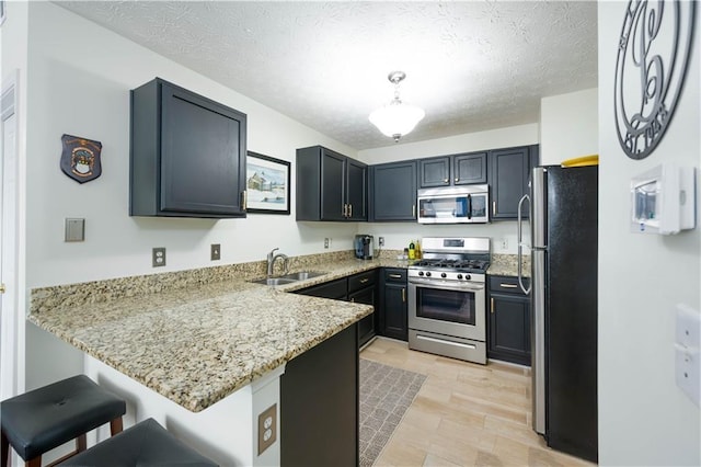 2305 Keenland Ct, Cumming, GA 30040 - kitchen with appliances with stainless steel finishes, a sink, a peninsula, light stone counters, and a breakfast bar area