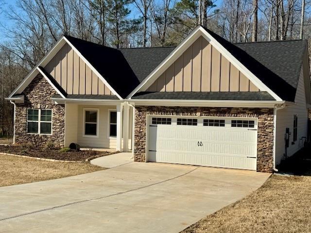 craftsman-style house featuring concrete driveway, a garage, board and batten siding, and stone siding