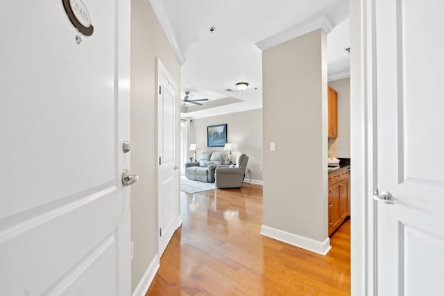 corridor with crown molding, light wood-style floors, and baseboards