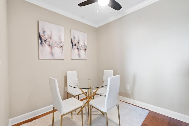 dining room with wood finished floors, ornamental molding, baseboards, and a ceiling fan