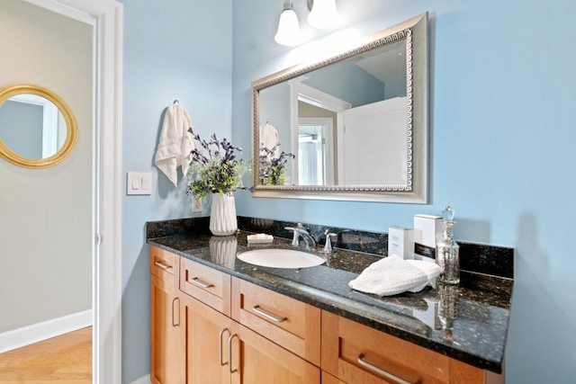bathroom featuring vanity, baseboards, and wood finished floors