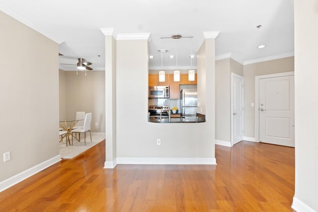 kitchen featuring appliances with stainless steel finishes, ornamental molding, wood finished floors, a ceiling fan, and baseboards