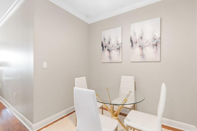 dining area with wood finished floors, ornamental molding, and baseboards