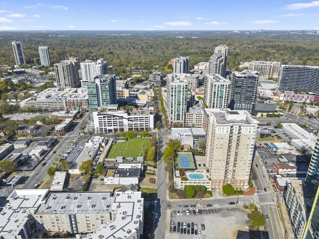aerial view of property and surrounding area with nearby urban area and a heavily wooded area