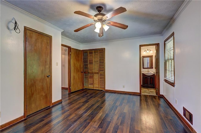 unfurnished bedroom with crown molding, wood finished floors, a textured ceiling, baseboards, and visible vents