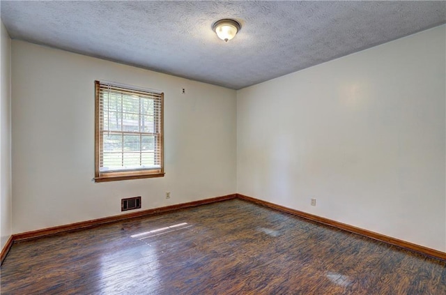 empty room featuring visible vents, baseboards, wood finished floors, and a textured ceiling