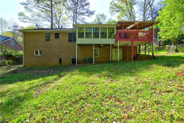 rear view of house with fence, a wooden deck, a sunroom, and a yard