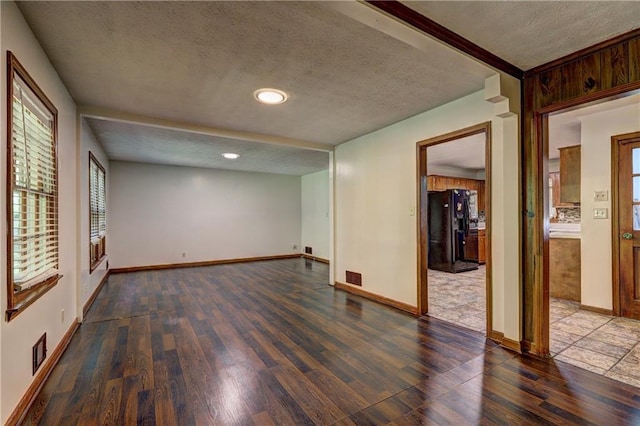 empty room featuring wood finished floors, a textured ceiling, baseboards, visible vents, and recessed lighting