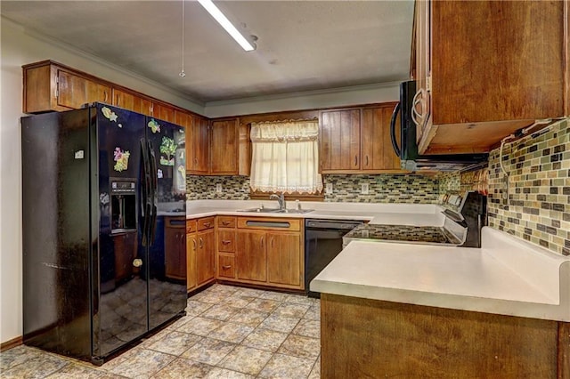 kitchen with brown cabinetry, a sink, black appliances, and tasteful backsplash