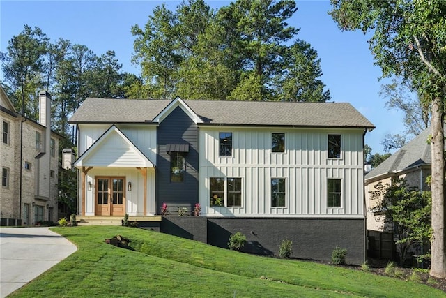 view of front facade featuring board and batten siding, a front lawn, and french doors