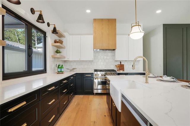 kitchen featuring light stone countertops, light wood-type flooring, stainless steel appliances, decorative light fixtures, and white cabinets