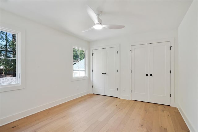 unfurnished bedroom with ceiling fan, light hardwood / wood-style floors, and multiple closets