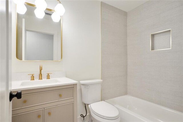 full bathroom featuring tiled shower / bath, vanity, and toilet