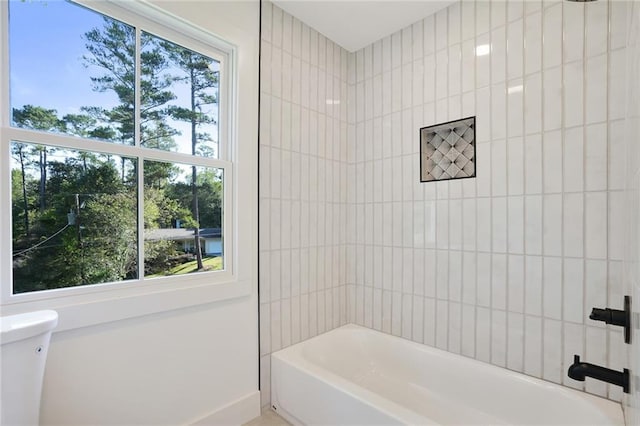 bathroom featuring toilet, shower / washtub combination, and a healthy amount of sunlight