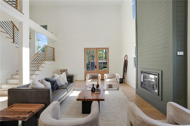 living room featuring a fireplace, a high ceiling, light wood-type flooring, and plenty of natural light