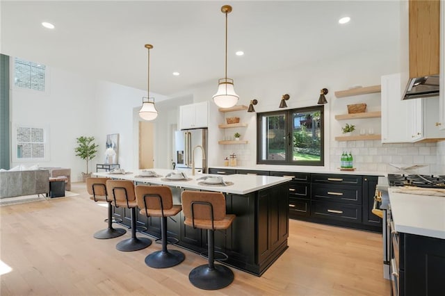 kitchen with decorative light fixtures, white cabinetry, plenty of natural light, and a kitchen island with sink