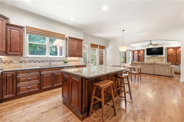2317 Whiting Bay Cts NW, Kennesaw, GA 30152 - kitchen with a breakfast bar area, light wood-style flooring, a kitchen island, ceiling fan, and decorative backsplash