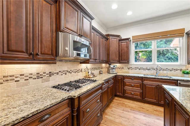 2317 Whiting Bay Cts NW, Kennesaw, GA 30152 - kitchen with appliances with stainless steel finishes, backsplash, crown molding, light stone counters, and light wood finished floors
