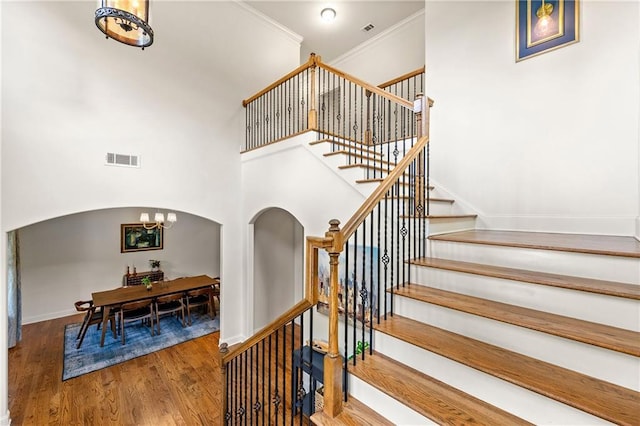 2317 Whiting Bay Cts NW, Kennesaw, GA 30152 - staircase featuring arched walkways, wood finished floors, a chandelier, a high ceiling, and crown molding